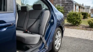 Open car door showing rear seat and buckled seatbelt in vehicle